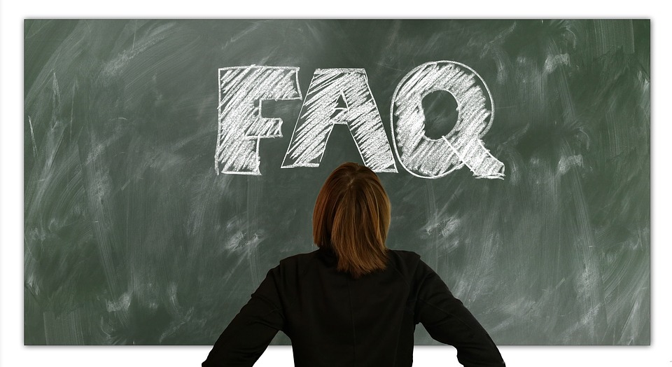 woman standing in front of a blackboard that says FAQ